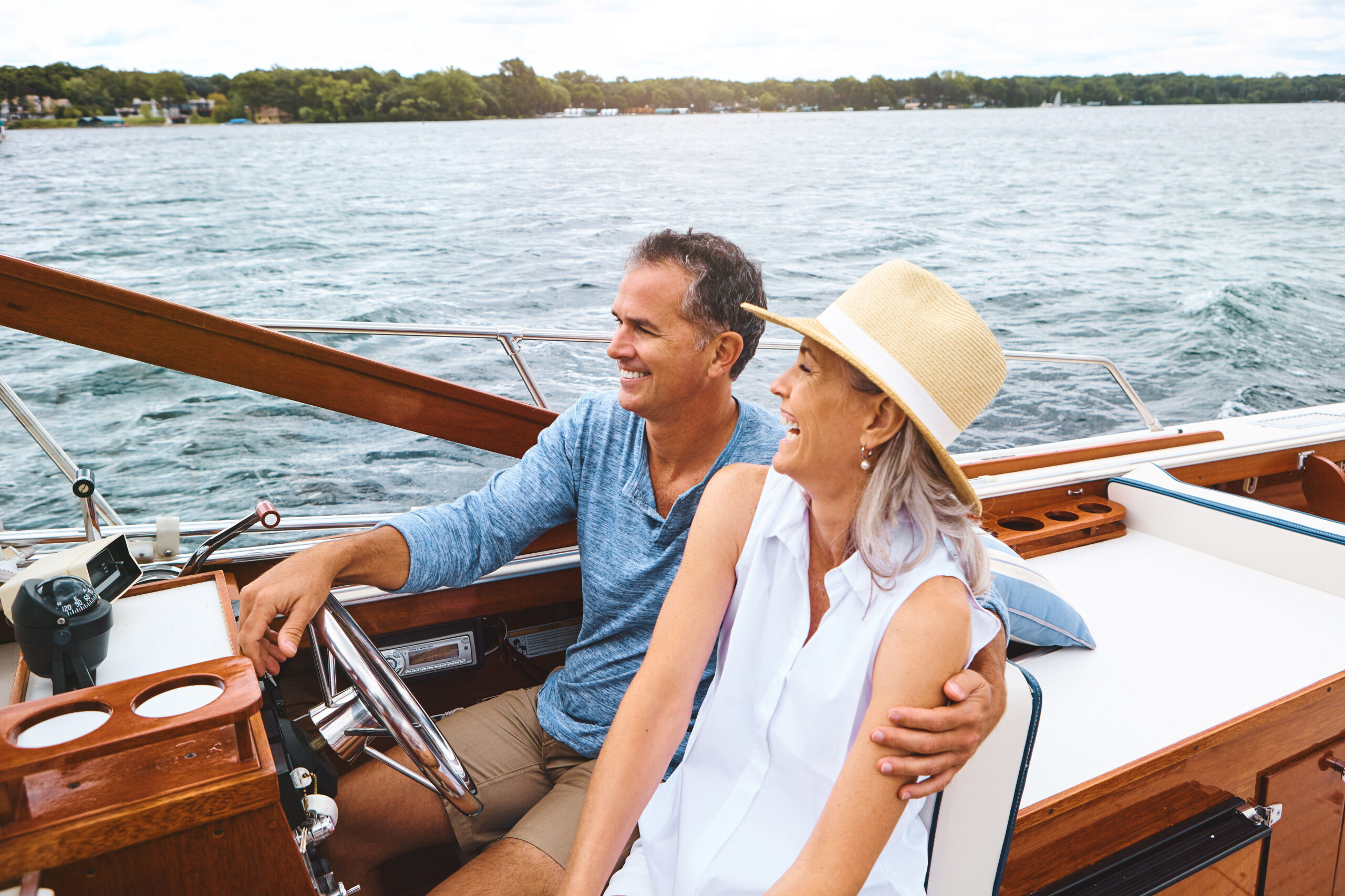 A couple smiles and laughs while on a boat on a large lake